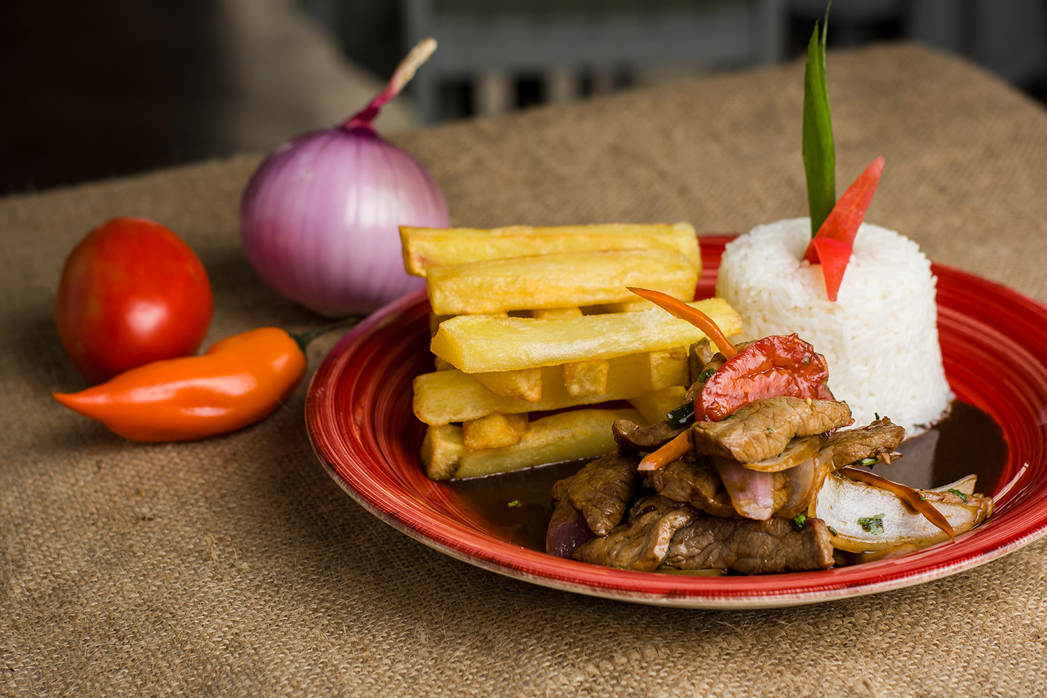 Lomo Saltado, a fusion of Peruvian and Chinese flavors, featuring stir-fried beef, onions, tomatoes, and yellow potatoes, served with rice.