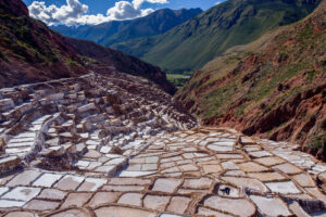 Maras Salt Mines in Peru’s Sacred Valley, with white salt terraces spreading across the mountainside and Andean peaks in the background.