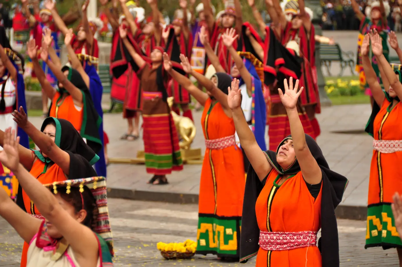 Traditional dancers with arms raised during Inti Raymi ceremony, Cusco